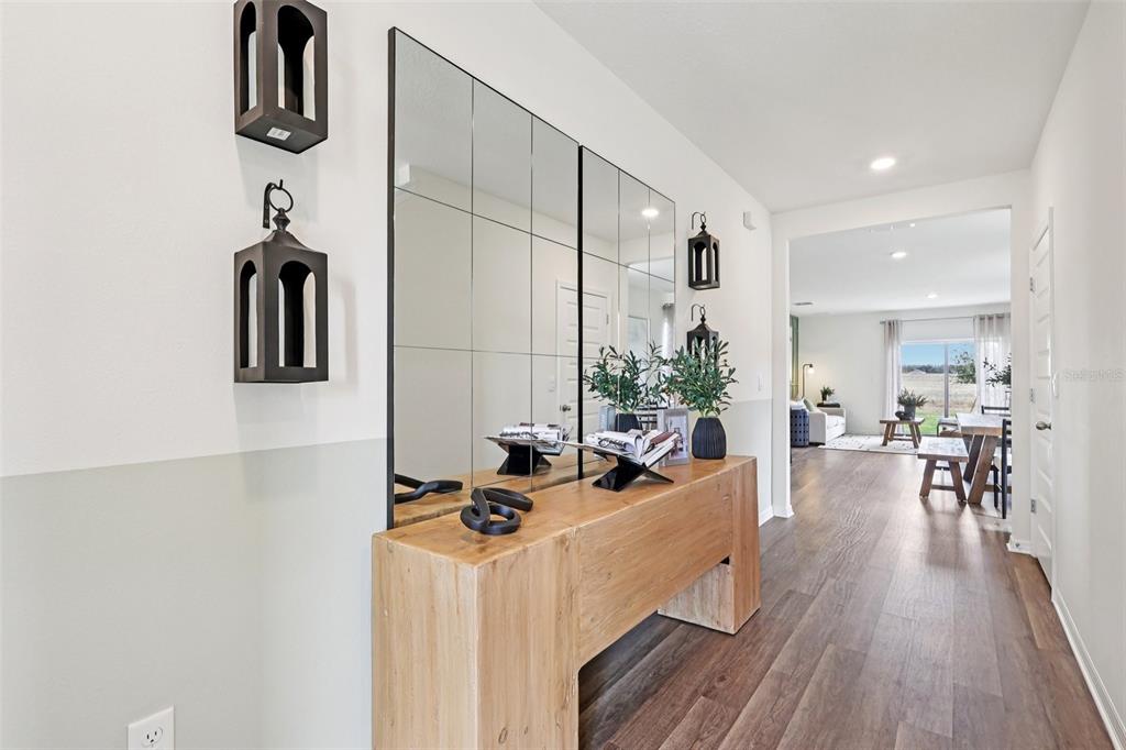 A wooden console table sits beneath a large grid mirror in a bright, modern entryway — 4209 BIXBY BRIDGE PLACE, DAVENPORT, FL