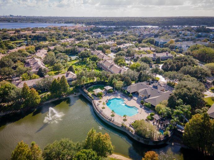An aerial view of a community swimming pool and fountain located next to a lake — 2679 METRO SEVILLA DRIVE UNIT 109, ORLANDO, FL