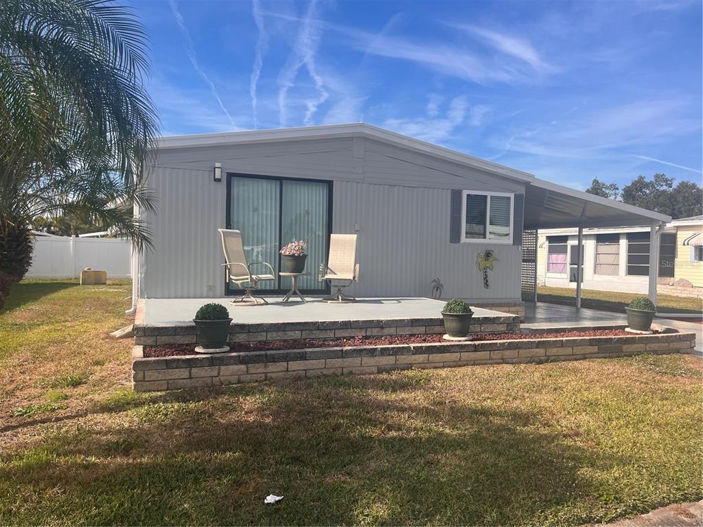 A light gray manufactured home features a front deck, a carport, and a palm tree — 5316 53RD AVENUE E UNIT O12, BRADENTON, FL