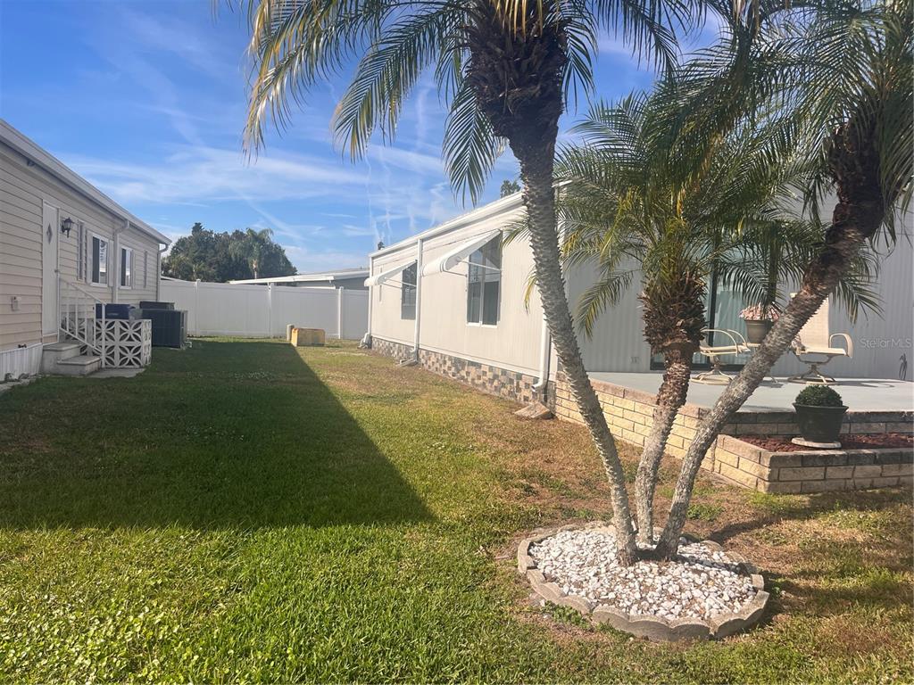 A living room features wood-paneled walls, light flooring, a mounted television, and blue armchairs — 5316 53RD AVENUE E UNIT O12, BRADENTON, FL