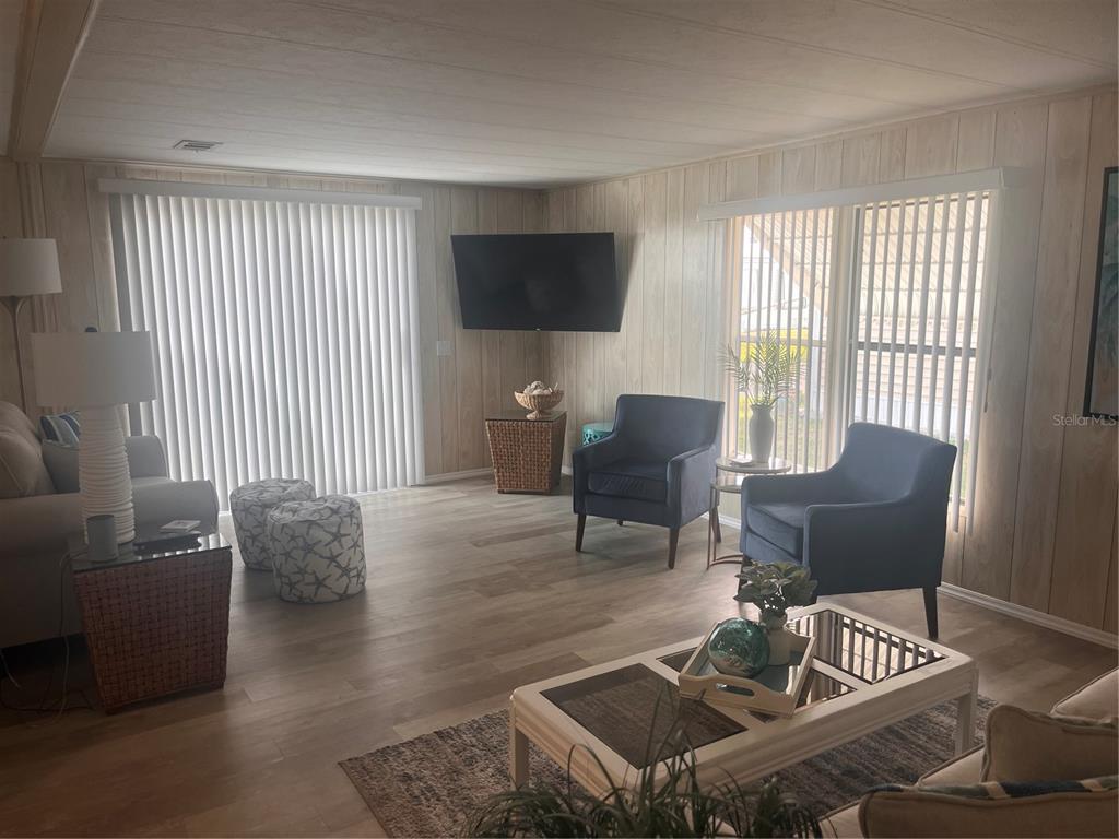 A living room features wood-paneled walls, a beige sofa, a blue armchair, and a rug — 5316 53RD AVENUE E UNIT O12, BRADENTON, FL