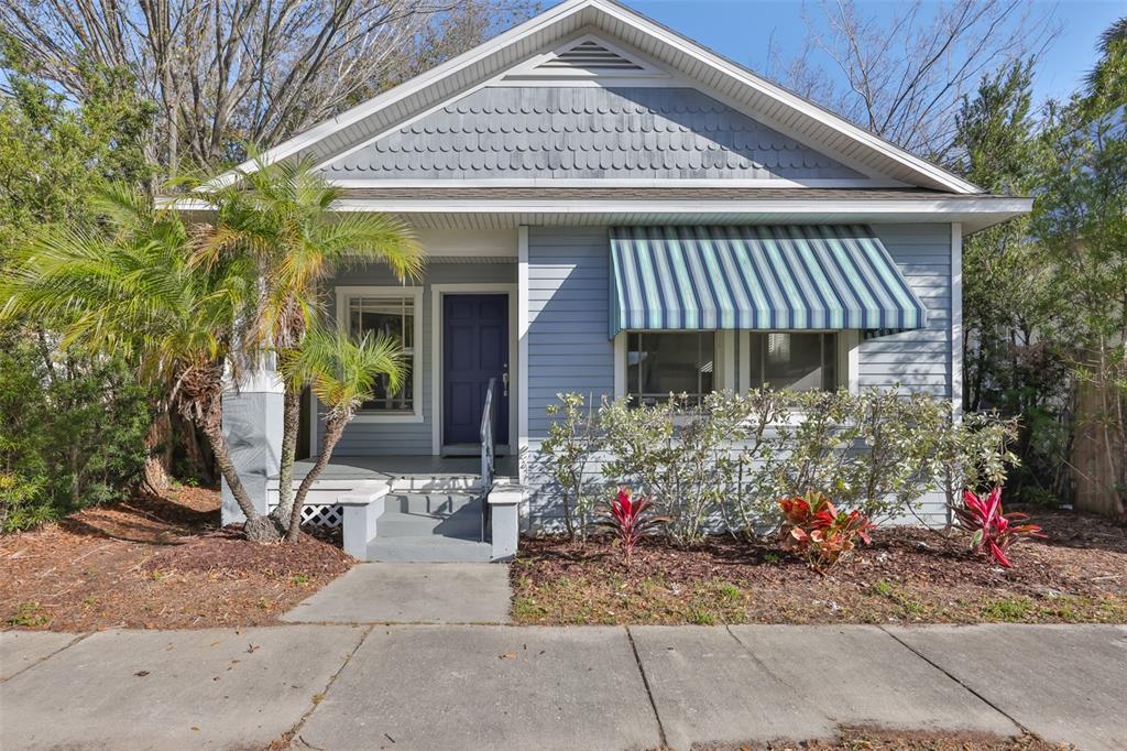A light blue bungalow with a front porch, striped awning, and a dark purple front door — 2331 W CHESTNUT STREET, TAMPA, FL