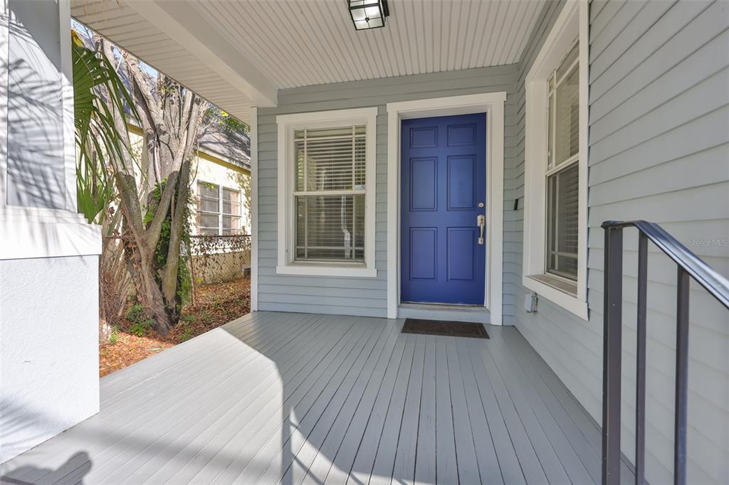 A covered front porch features light gray wood decking, blue siding, and a blue front door — 2331 W CHESTNUT STREET, TAMPA, FL