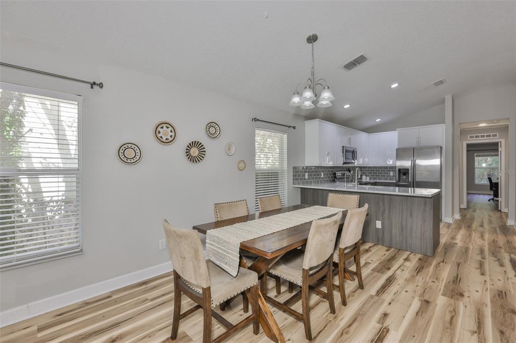 A dining area with a wooden table, upholstered chairs, and an adjacent kitchen with island — 2331 W CHESTNUT STREET, TAMPA, FL