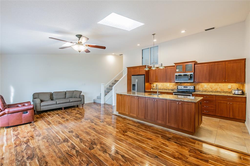 An open-concept kitchen and living area features wood flooring, wooden cabinetry, and a central island — 6435 92ND PLACE UNIT 904, PINELLAS PARK, FL