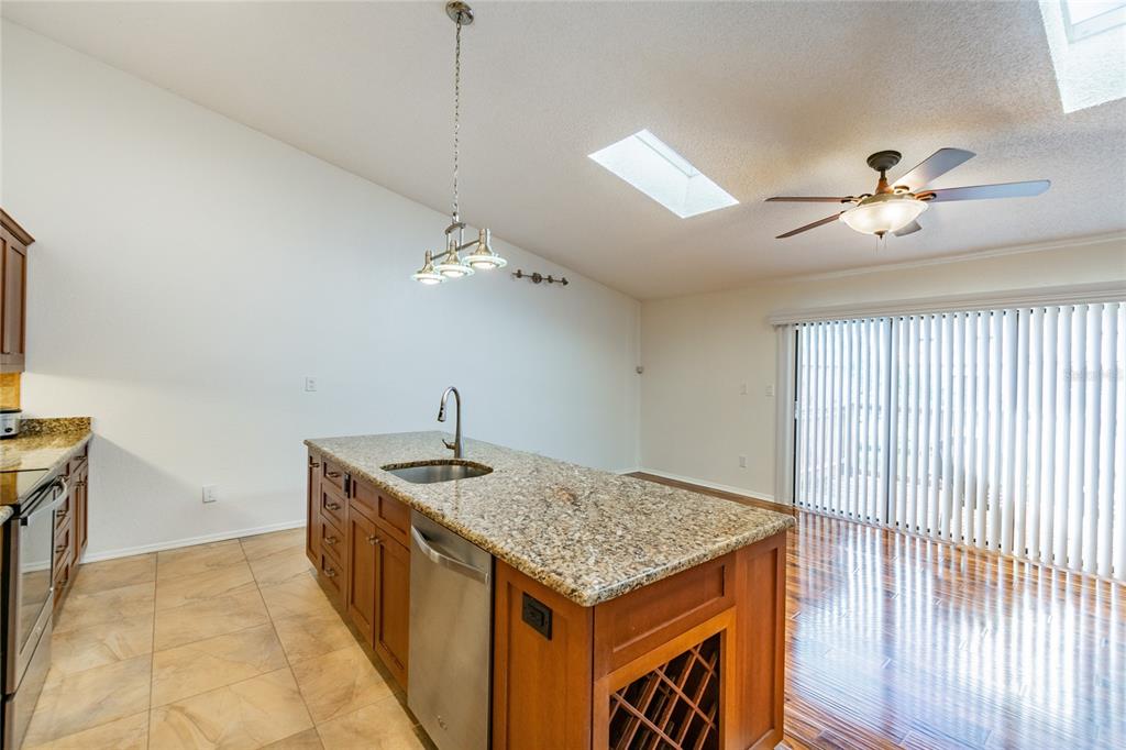 A kitchen island with a granite countertop and sink sits in a room with skylights — 6435 92ND PLACE UNIT 904, PINELLAS PARK, FL