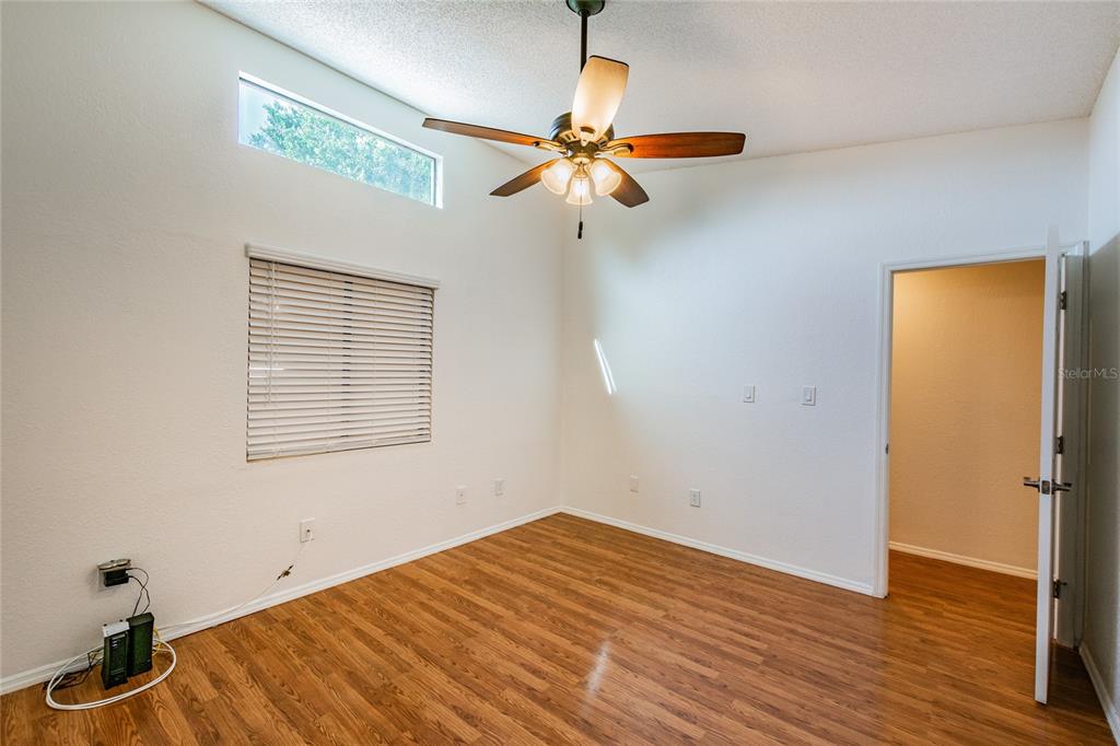 An empty bedroom with wood-look flooring, a ceiling fan, and a high window — 6435 92ND PLACE UNIT 904, PINELLAS PARK, FL