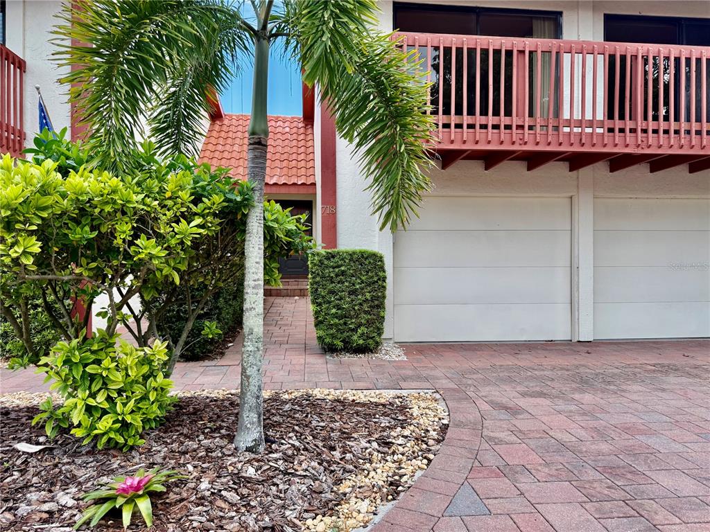 A palm tree stands before a two-story building with a garage and a brick driveway — 718 SORRENTO INLET DRIVE UNIT 718, NOKOMIS, FL