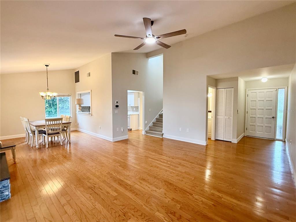 An open-concept living and dining area features hardwood floors, vaulted ceilings, and a staircase — 718 SORRENTO INLET DRIVE UNIT 718, NOKOMIS, FL