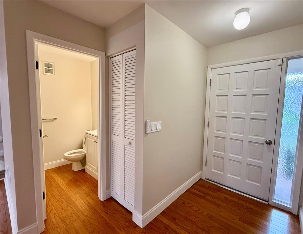 A foyer with hardwood floors, a white front door, a closet, and a half bathroom — 718 SORRENTO INLET DRIVE UNIT 718, NOKOMIS, FL