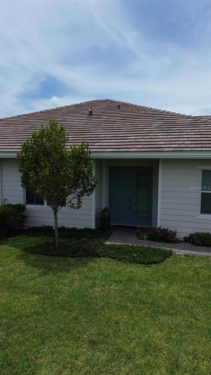 A single-story house with a tiled roof, light siding, and a double front door — 19610 WEATHERVANE WAY, LOXAHATCHEE, FL