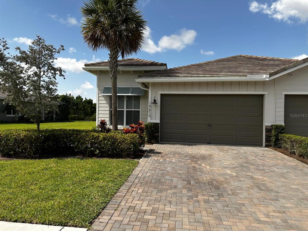 A single-story house exterior features a paved driveway, a two-car garage, and a palm tree — 19610 WEATHERVANE WAY, LOXAHATCHEE, FL