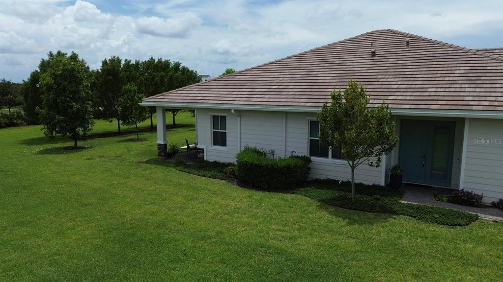 An exterior view of a house with a tiled roof, light siding, and a grassy yard — 19610 WEATHERVANE WAY, LOXAHATCHEE, FL