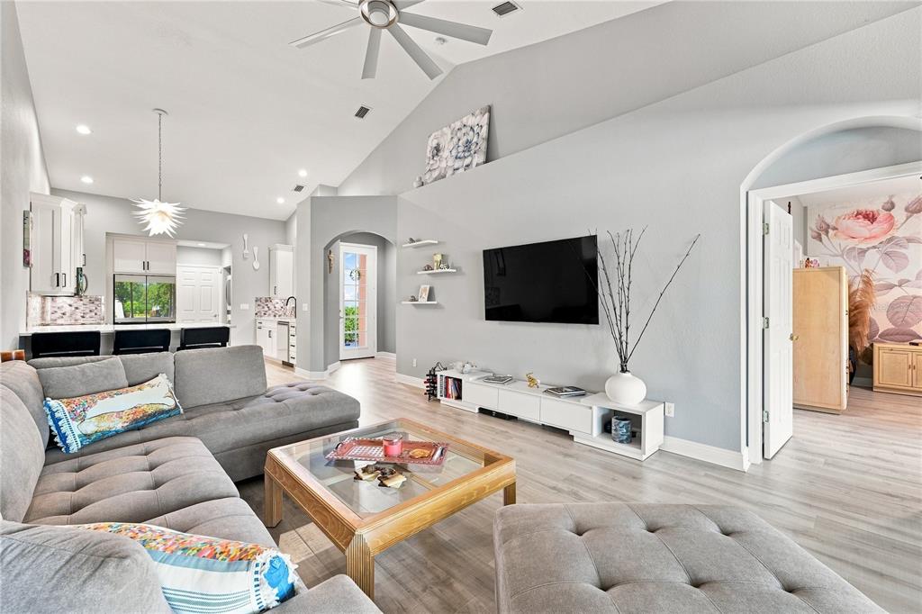 A living room features a gray sectional sofa, a glass coffee table, and a wall-mounted television — 4361 TURNBERRY CIRCLE, NORTH PORT, FL