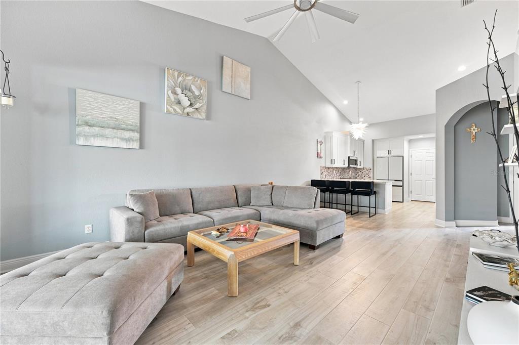 A living room with a gray sectional sofa, wooden coffee table, and open kitchen area — 4361 TURNBERRY CIRCLE, NORTH PORT, FL