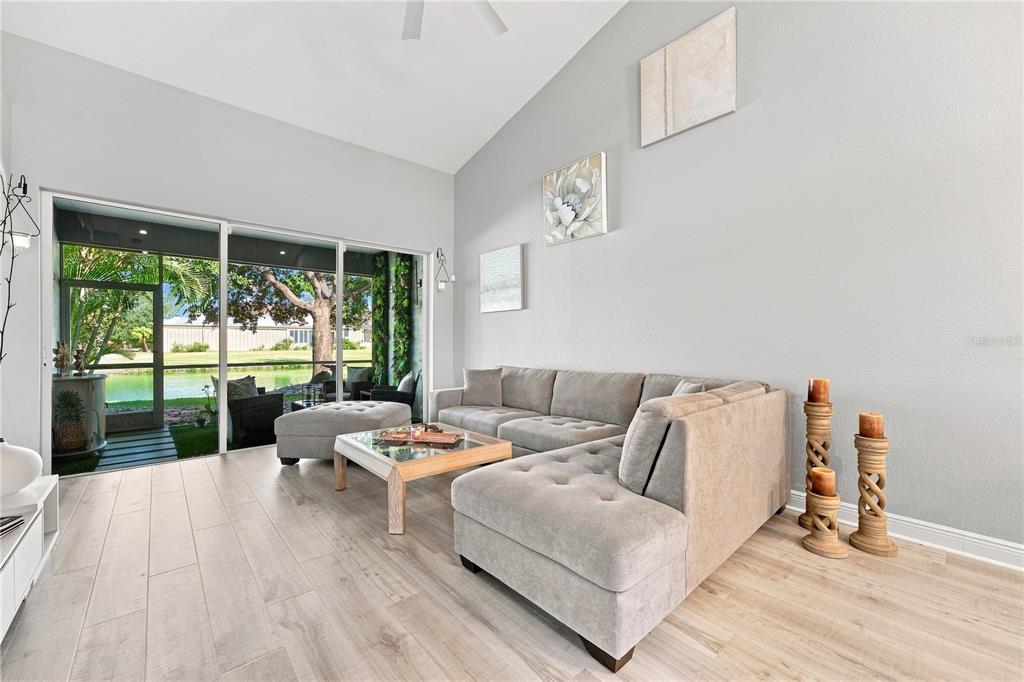 A living room features a grey sectional sofa, light wood flooring, and sliding glass doors — 4361 TURNBERRY CIRCLE, NORTH PORT, FL