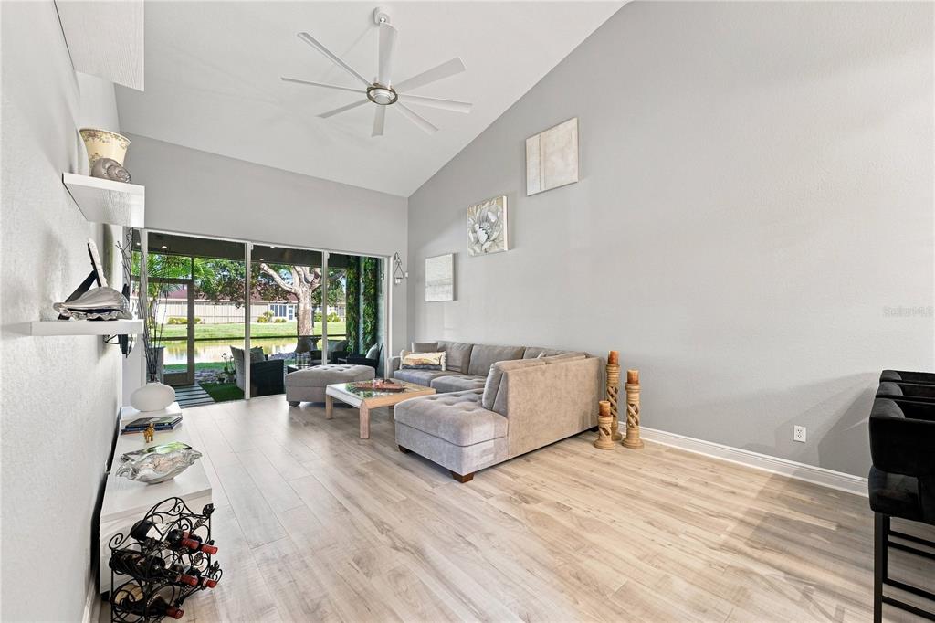 A living room features light wood flooring, a gray sectional sofa, and sliding glass doors — 4361 TURNBERRY CIRCLE, NORTH PORT, FL
