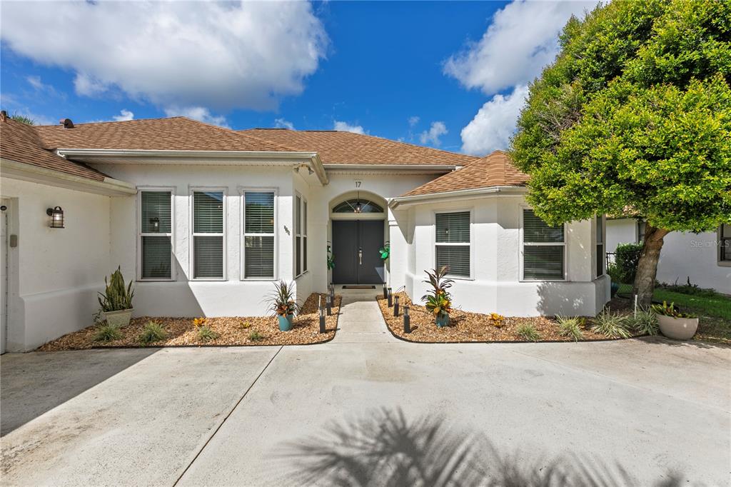A single-story house with a white stucco exterior, brown shingle roof, and a concrete driveway — 17 COLLINGTON COURT, PALM COAST, FL