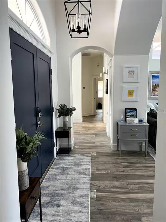 A bright entryway features dark blue double doors, wood-look flooring, and a modern geometric pendant light — 17 COLLINGTON COURT, PALM COAST, FL