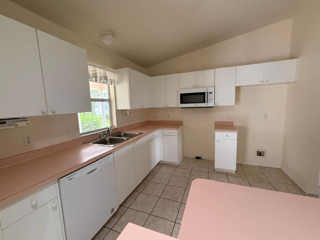 A kitchen features white cabinets, pink countertops, a double sink, and a white dishwasher — 208 ARAGON LANE, LADY LAKE, FL