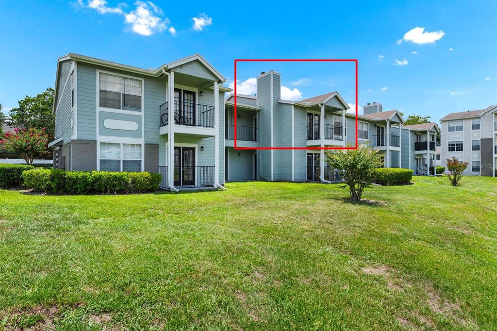 A multi-story apartment building exterior with a red box highlighting an upper-level balcony — 2550 N ALAFAYA TRAIL UNIT 1203, ORLANDO, FL