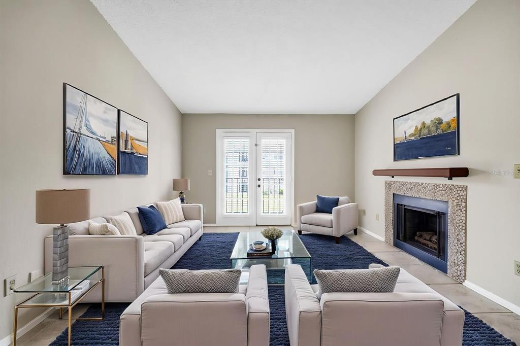 A living room features a fireplace, a sofa, three armchairs, and a glass coffee table — 2550 N ALAFAYA TRAIL UNIT 1203, ORLANDO, FL