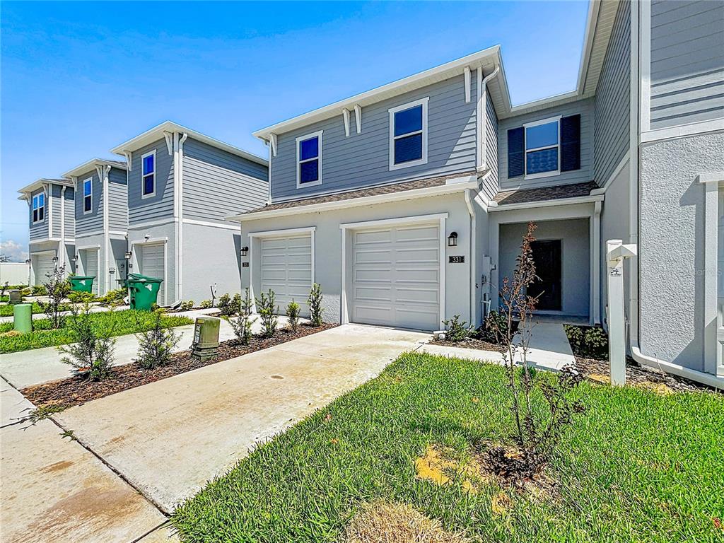 The exterior of a two-story townhouse features gray siding, a garage, and a front lawn — 331 SOL VISTA DRIVE, DUNDEE, FL