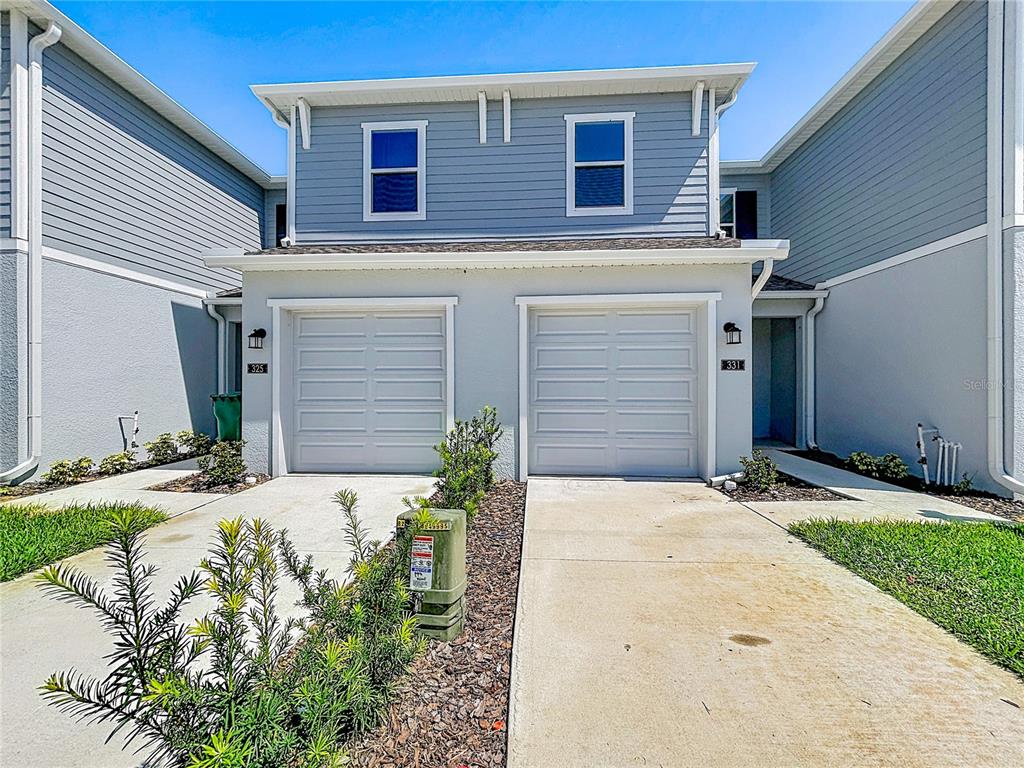 A two-story duplex with light blue siding, white trim, and two attached single-car garages — 331 SOL VISTA DRIVE, DUNDEE, FL