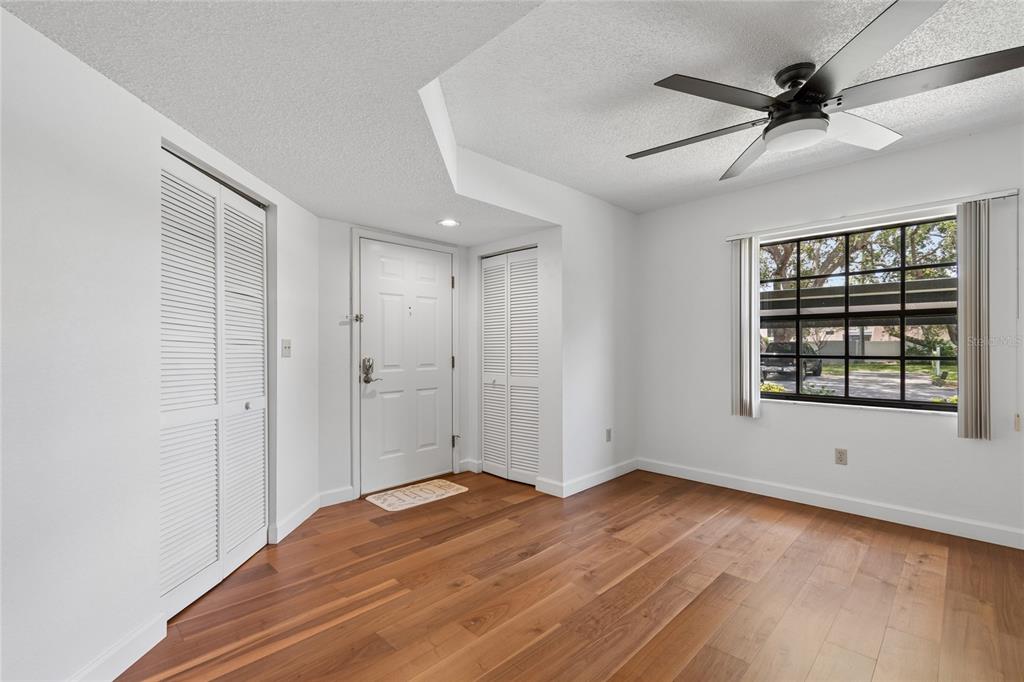 An entryway with wood flooring, white walls, two louvered closets, and a ceiling fan — 11800 PARK BOULEVARD UNIT 401, SEMINOLE, FL