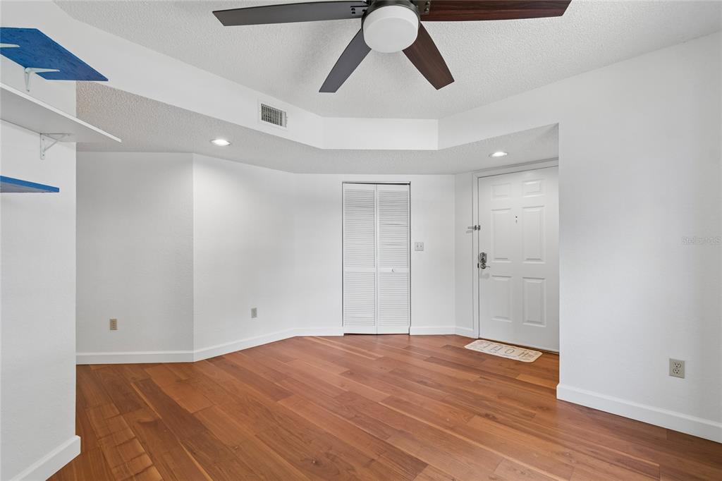 An empty room with white walls, wood flooring, a ceiling fan, and a white door — 11800 PARK BOULEVARD UNIT 401, SEMINOLE, FL