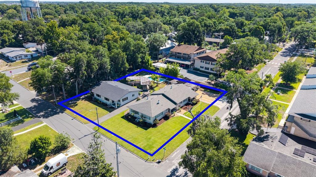 An aerial view shows two single-story houses on a corner lot with a swimming pool — 1012 N BAKER STREET, MOUNT DORA, FL