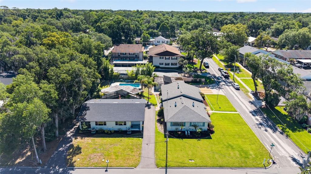 An aerial view shows two adjacent residential buildings with dark roofs and surrounding green lawns — 1012 N BAKER STREET, MOUNT DORA, FL
