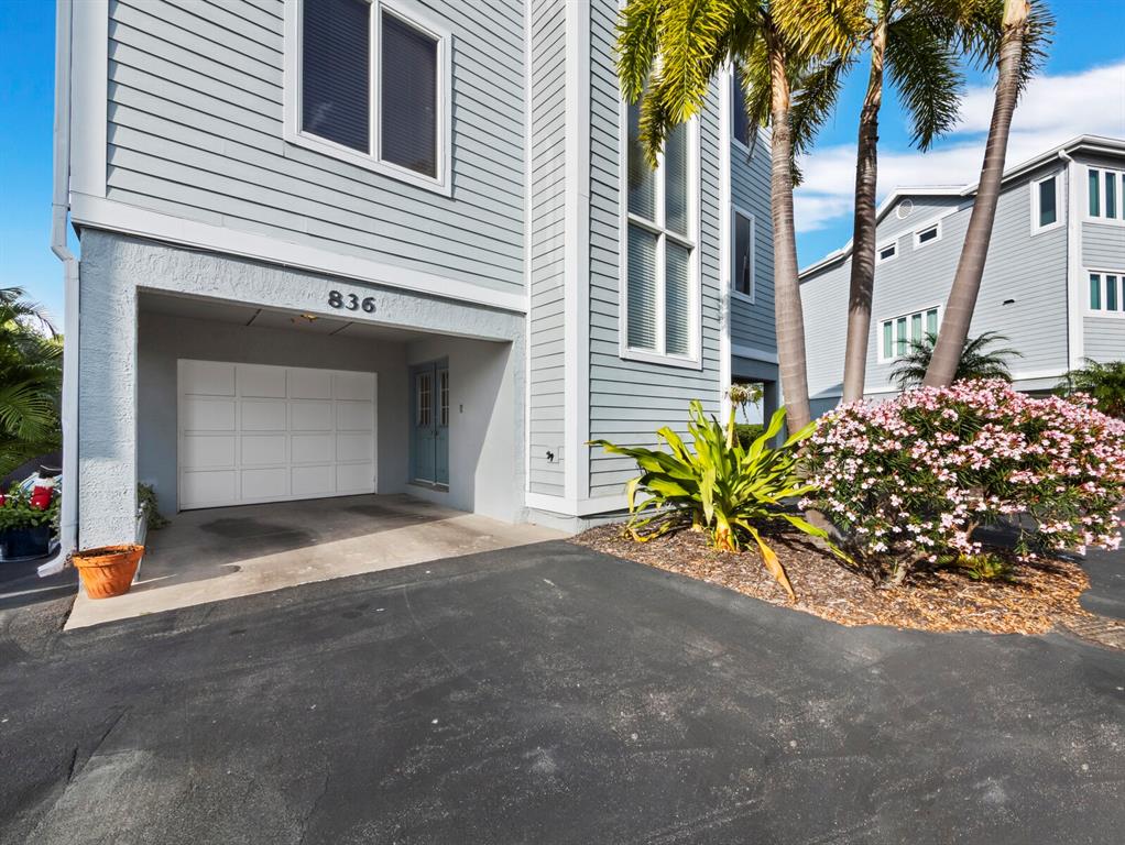 A light blue house exterior features a ground-level garage, a front door, and palm trees — 836 EVERGREEN WAY, LONGBOAT KEY, FL