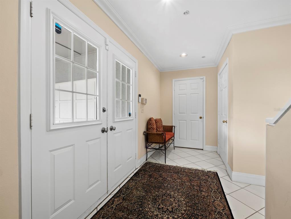 An entryway features white double doors, tiled flooring, a patterned rug, and a small bench — 836 EVERGREEN WAY, LONGBOAT KEY, FL