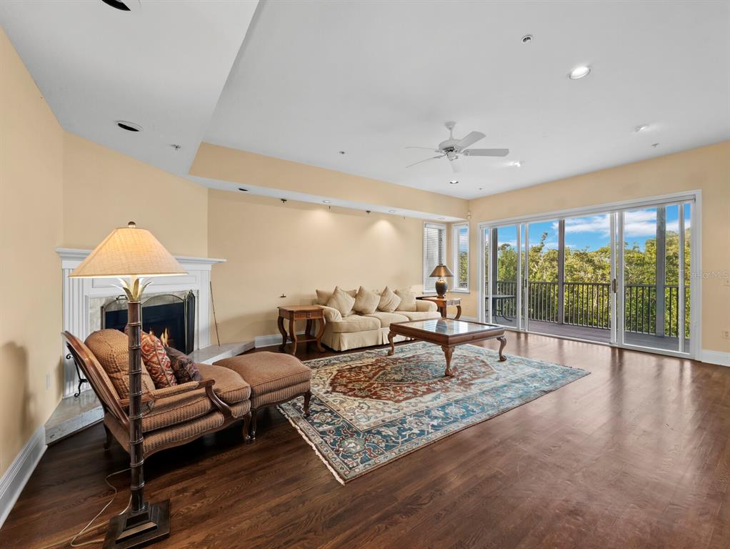 A living room with hardwood floors, a fireplace, a sofa, and sliding glass doors to a balcony — 836 EVERGREEN WAY, LONGBOAT KEY, FL