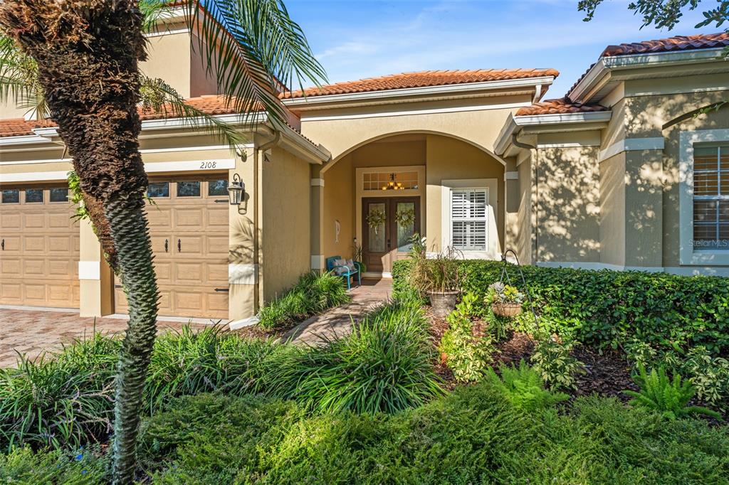 The exterior of a single-story house features a tan stucco facade, tile roof, and garage — 2108 TILLMAN AVENUE, WINTER GARDEN, FL