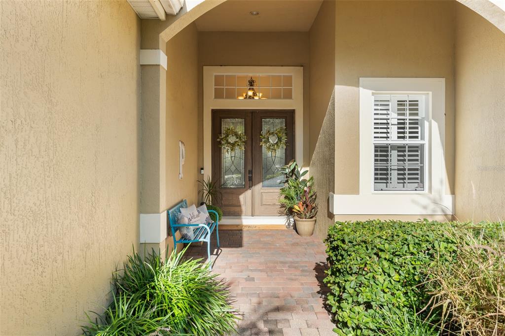 A front entryway features a brick porch, double wooden doors, and a blue metal bench — 2108 TILLMAN AVENUE, WINTER GARDEN, FL