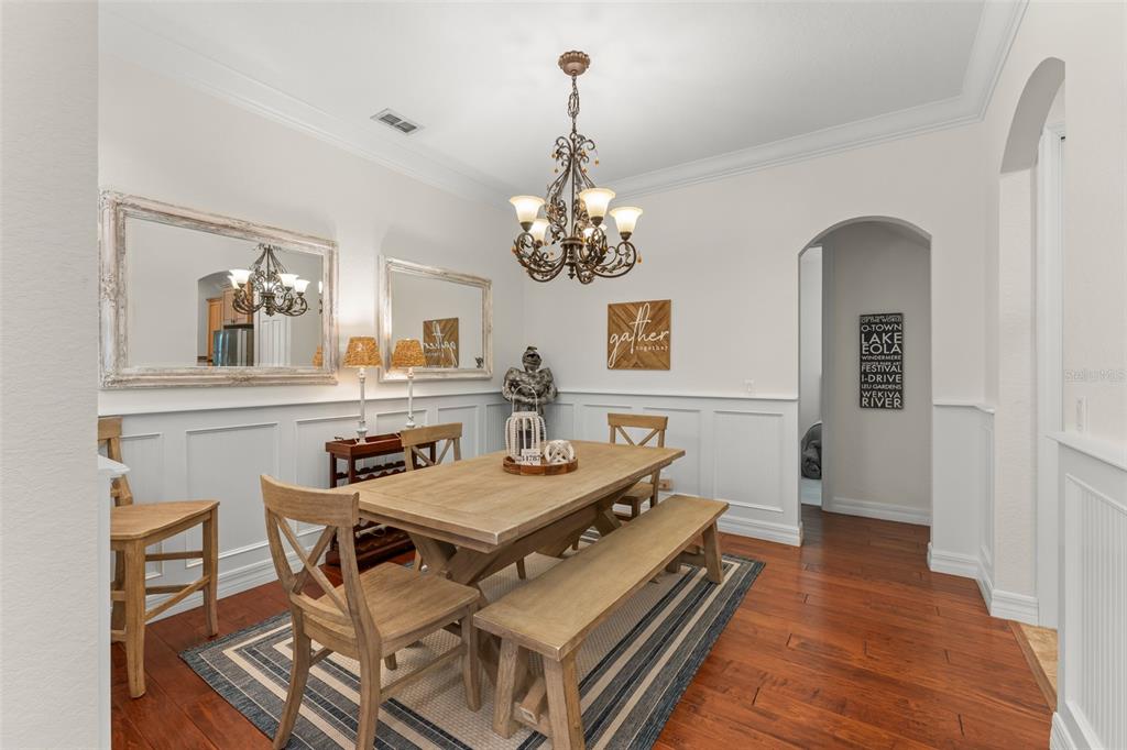 A dining room features a wooden table with a bench, wainscoting, and a chandelier — 2108 TILLMAN AVENUE, WINTER GARDEN, FL
