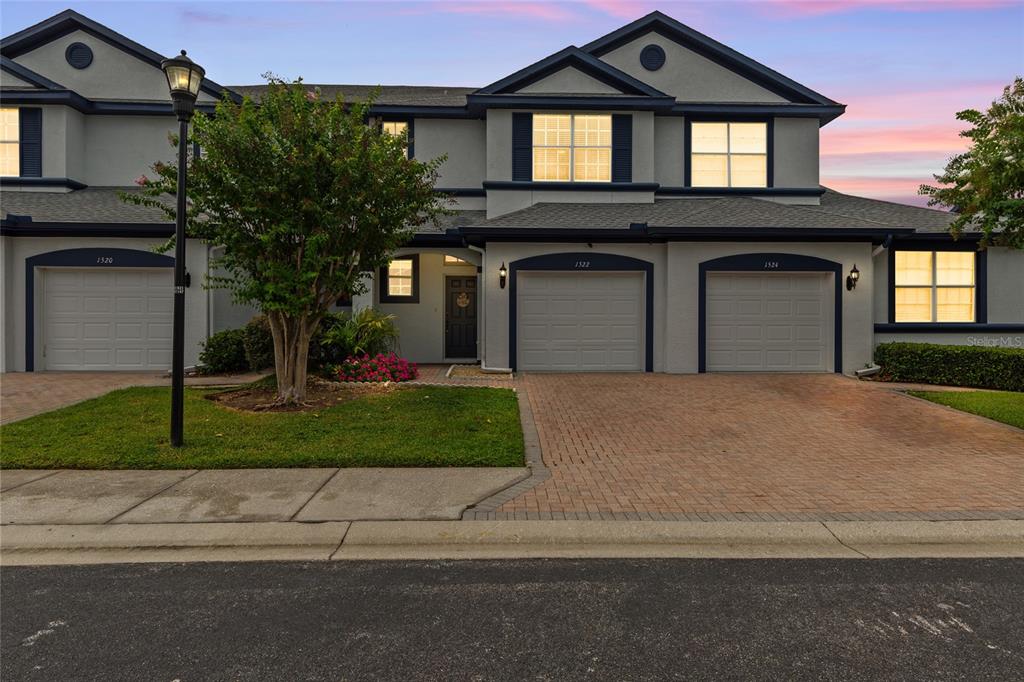 A multi-unit residential building features gray stucco siding, multiple garage doors, and a paved driveway — 1522 SUMMERGATE DRIVE, VALRICO, FL