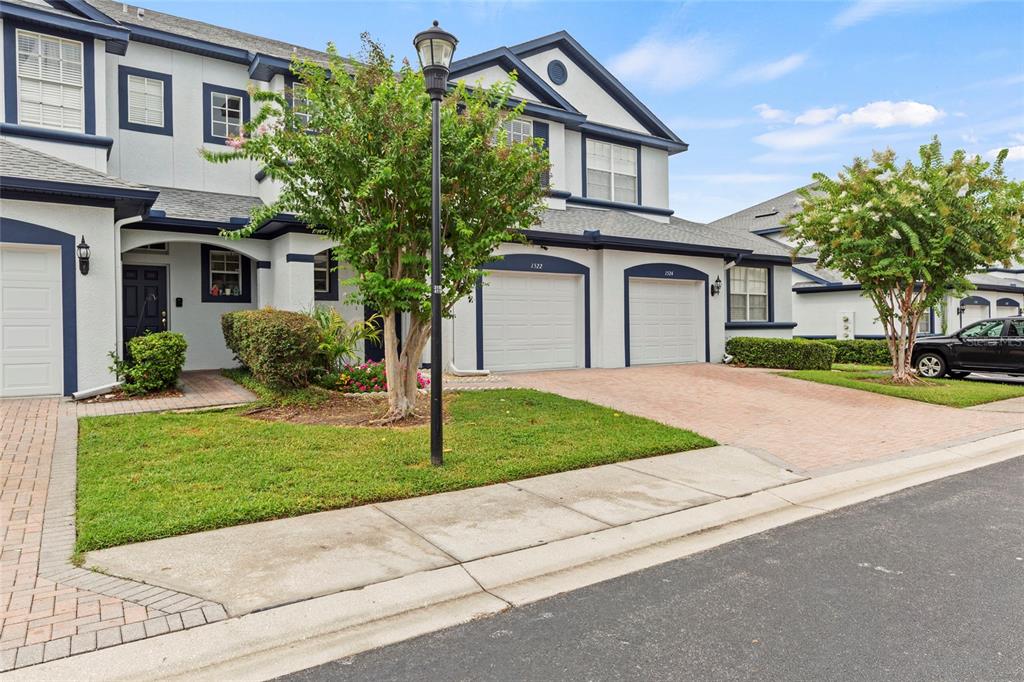 A two-story townhouse exterior features white stucco walls, blue trim, and two garage doors — 1522 SUMMERGATE DRIVE, VALRICO, FL