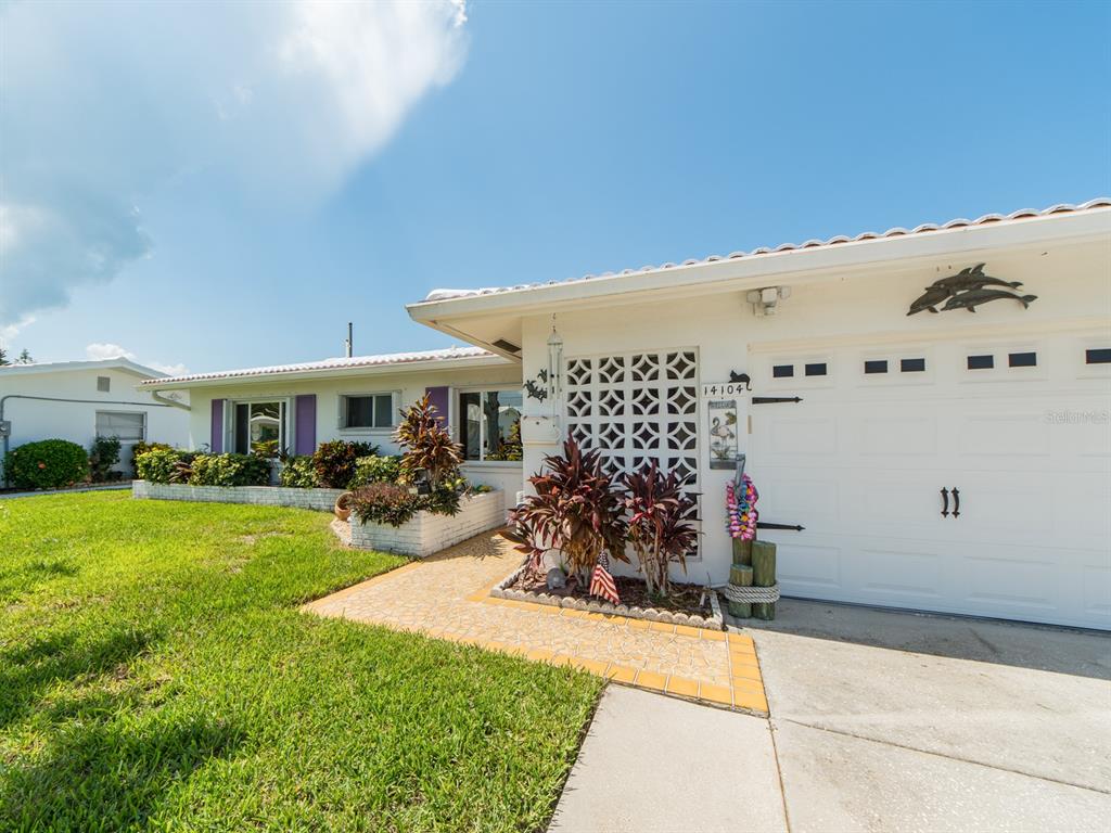 A single-story house exterior features a white garage, a decorative breeze block wall, and landscaping — 14104 89TH AVENUE, SEMINOLE, FL