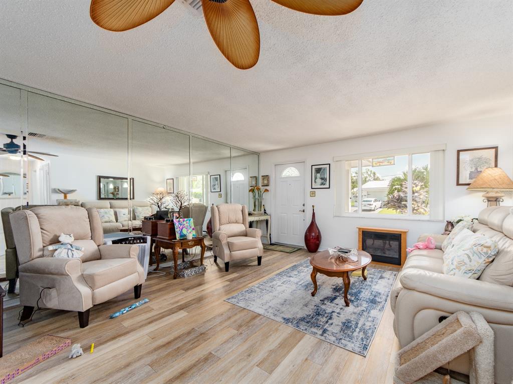A living room features light wood flooring, a mirrored wall, beige armchairs, and a sofa — 14104 89TH AVENUE, SEMINOLE, FL