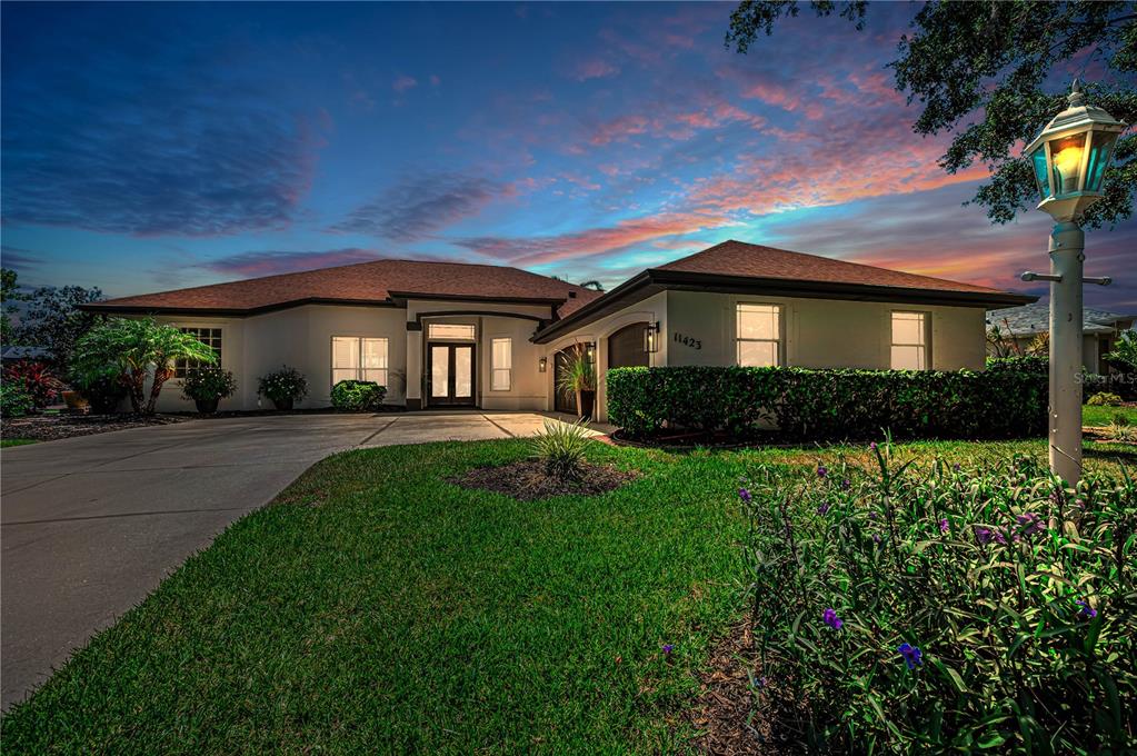 A single-story house with a concrete driveway and a lamp post at dusk — 11423 30TH COVE E, PARRISH, FL