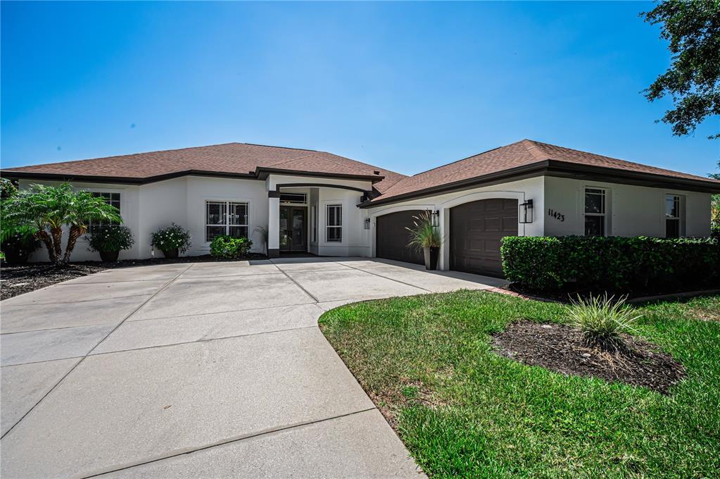 A single-story house with a white exterior, brown roof, and a concrete driveway — 11423 30TH COVE E, PARRISH, FL