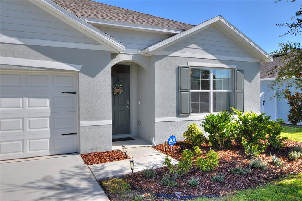 The exterior of a single-story house features light gray stucco, a garage, and a front entrance — 3645 DIVING DOVE LANE, BARTOW, FL