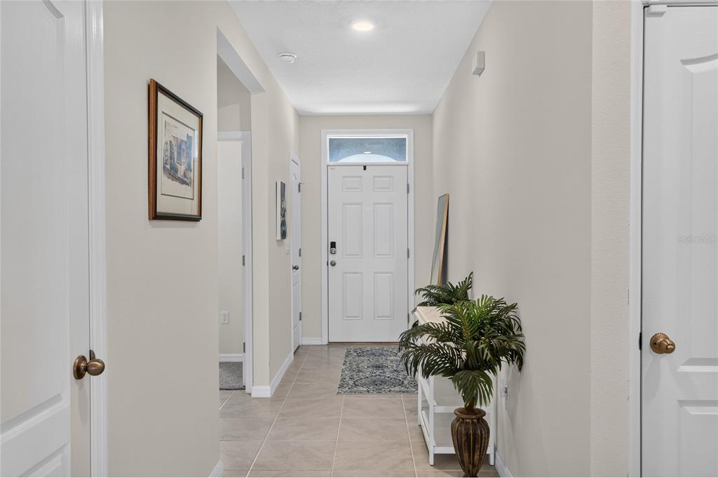 A tiled hallway leads from an entryway toward a windowed room in the distance — 3645 DIVING DOVE LANE, BARTOW, FL