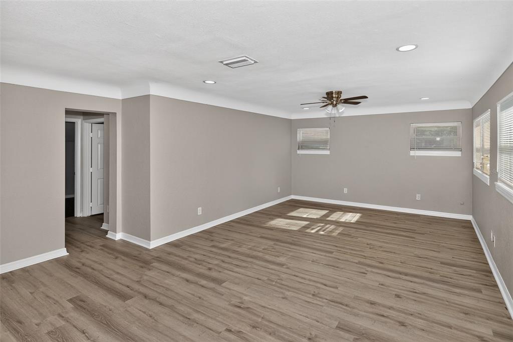 A living room with gray walls, wood-look flooring, a ceiling fan, and an adjacent kitchen — 5131 ARAGON WAY S, ST PETERSBURG, FL
