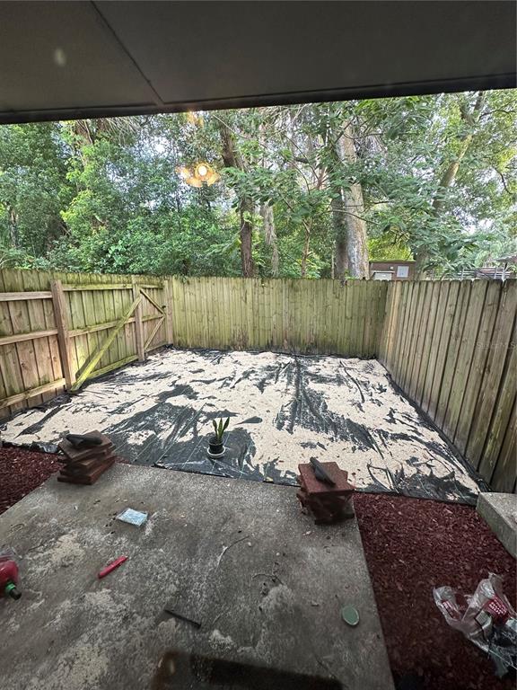 A fenced backyard features a concrete patio and a ground area covered with landscape fabric — 1910 W SLIGH AVENUE UNIT E102, TAMPA, FL