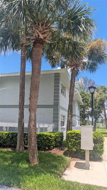 A two-story building with gray trim and palm trees stands next to a sidewalk — 458 FAIRWAYS CIRCLE UNIT C201, OCALA, FL