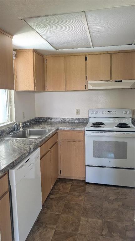 A kitchen features light wood cabinets, a white stove, a dishwasher, and a laminate countertop — 458 FAIRWAYS CIRCLE UNIT C201, OCALA, FL